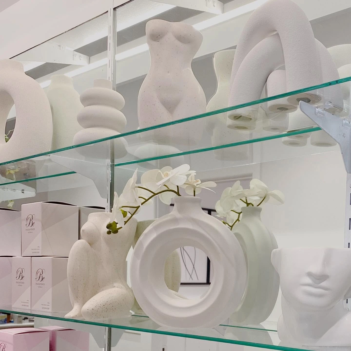Ceramic vases and Be Enlightened candles on glass shelves